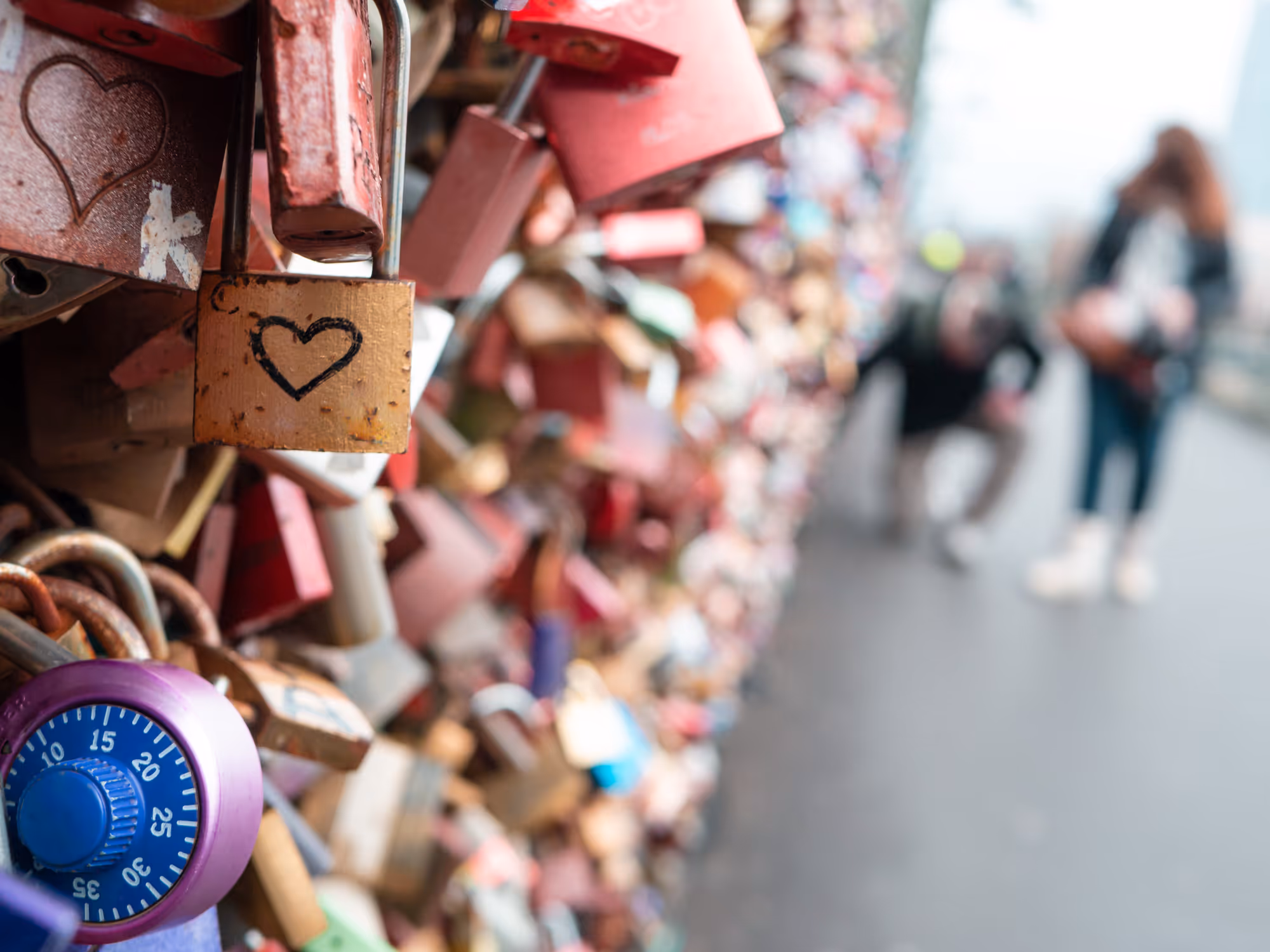 Liebesschlösser an der Hohenzollernbrücke in Köln mit Paar im Hintergrund