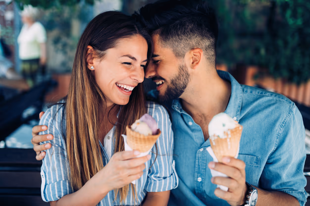 Ein Paar lacht gemeinsam und isst dabei jeweils ein Eis