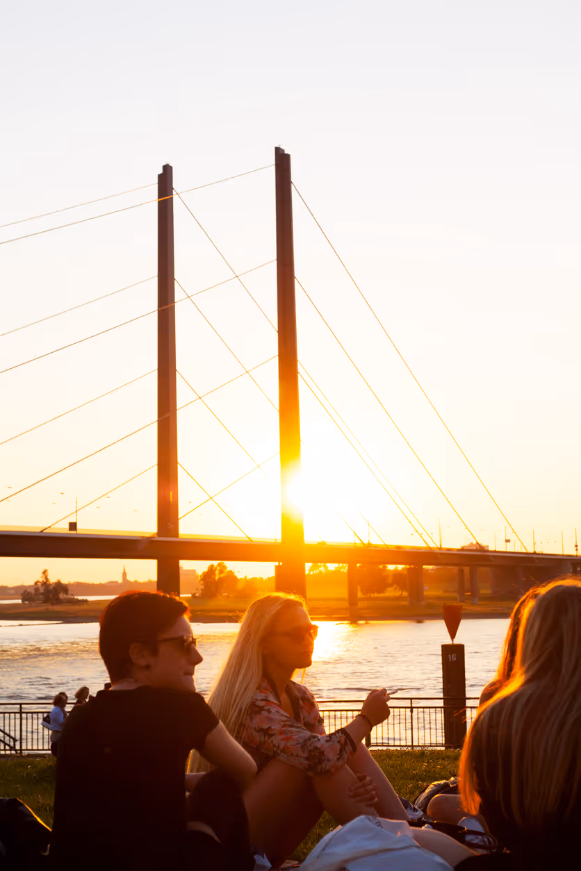 Junge Leute in Düsseldorf am Rheinufer bei Sonnenuntergang