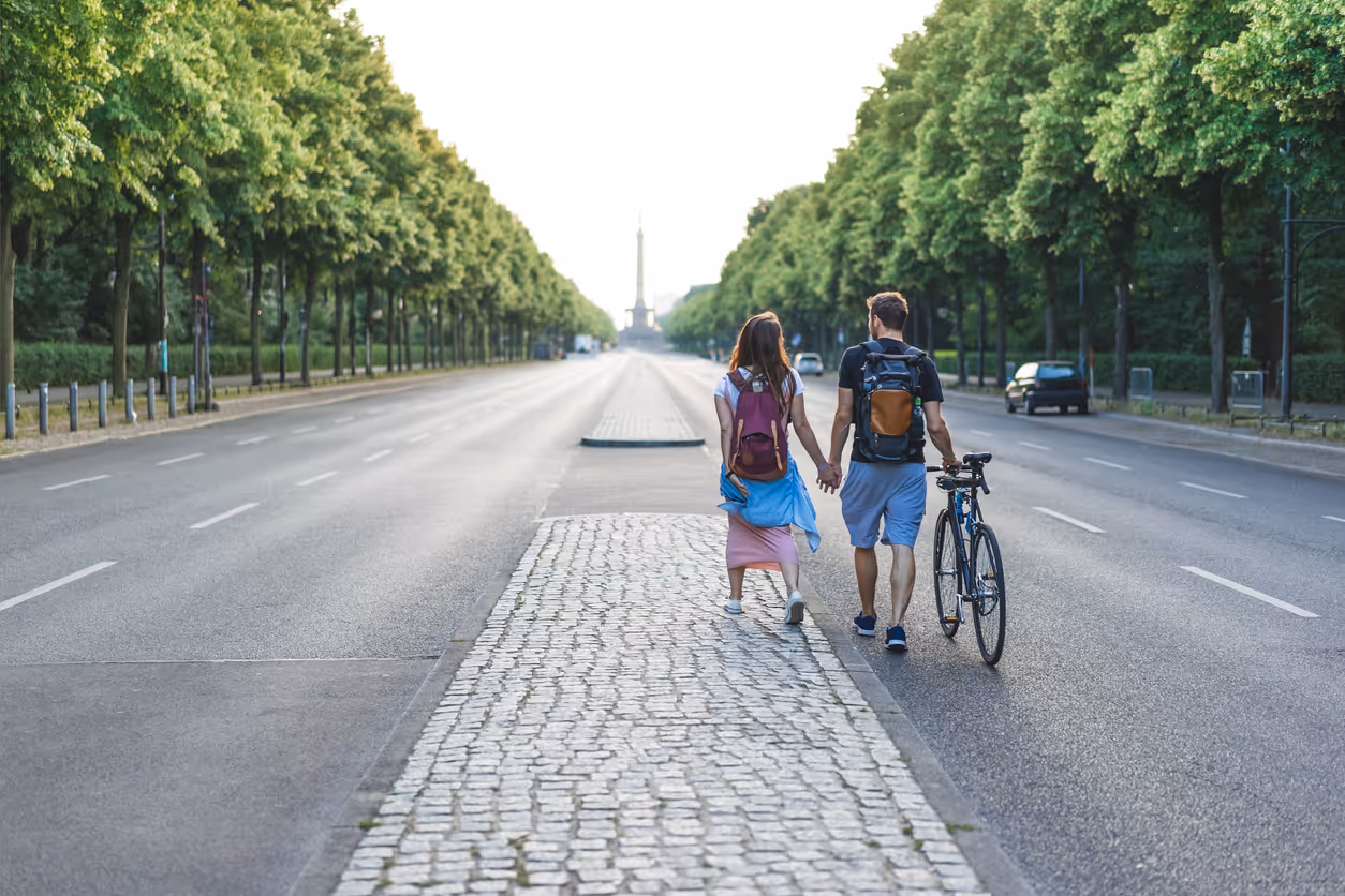Zwei Personen halten Händchen, während sie eine Straße in Berlin entlang gehen