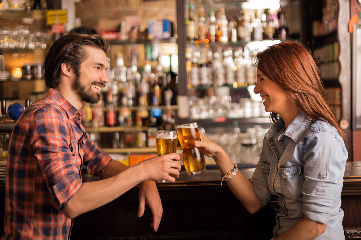 Paar trinkt an einer Bar in einer Kneipe Bier und stößt an