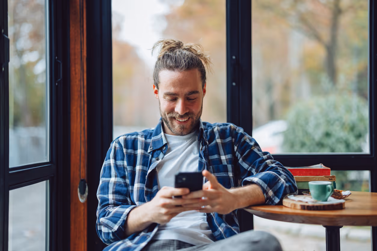 Glücklicher Mann am Handy im Café