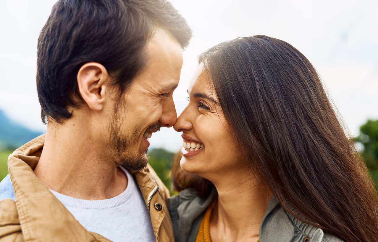 Ein Mann und eine Frau stehen sich Nase an Nase gegenüber und lachen sich gegenseitig an