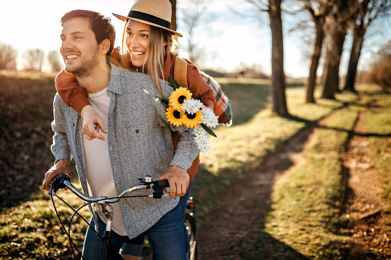 Glückliches Paar auf einem Fahrrad mit Sonnenblumen in der Hand