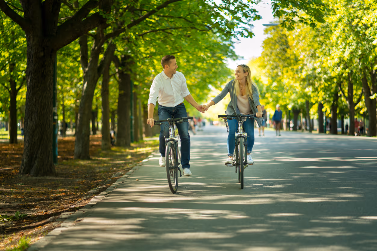 Mann und Frau halten Händchen beim Fahrradfahren auf der Promenade in Münster