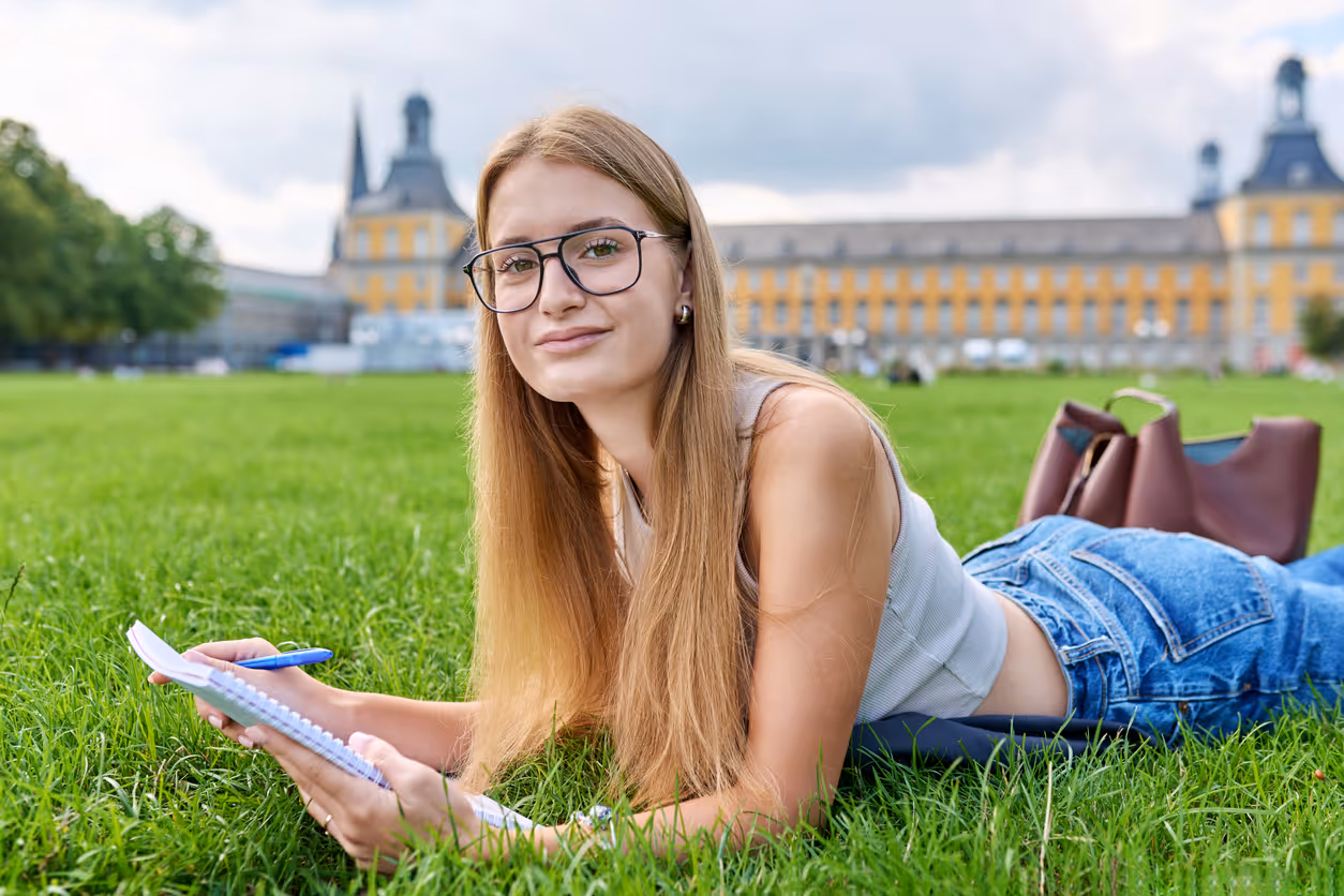 Junge Studentin lernt auf dem Gras vor dem Poppelsdorfer Schloss in Bonn.