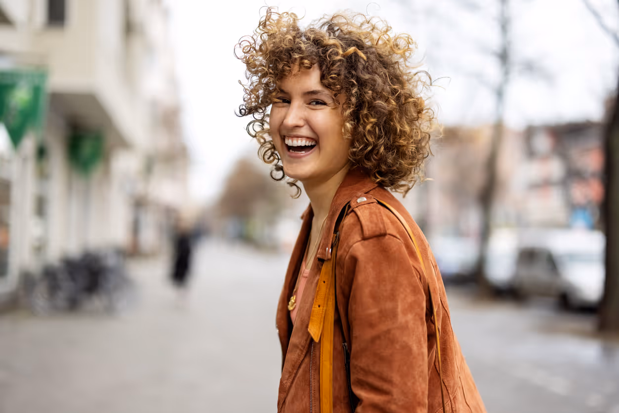 Eine junge Frau steht im Freien und lacht