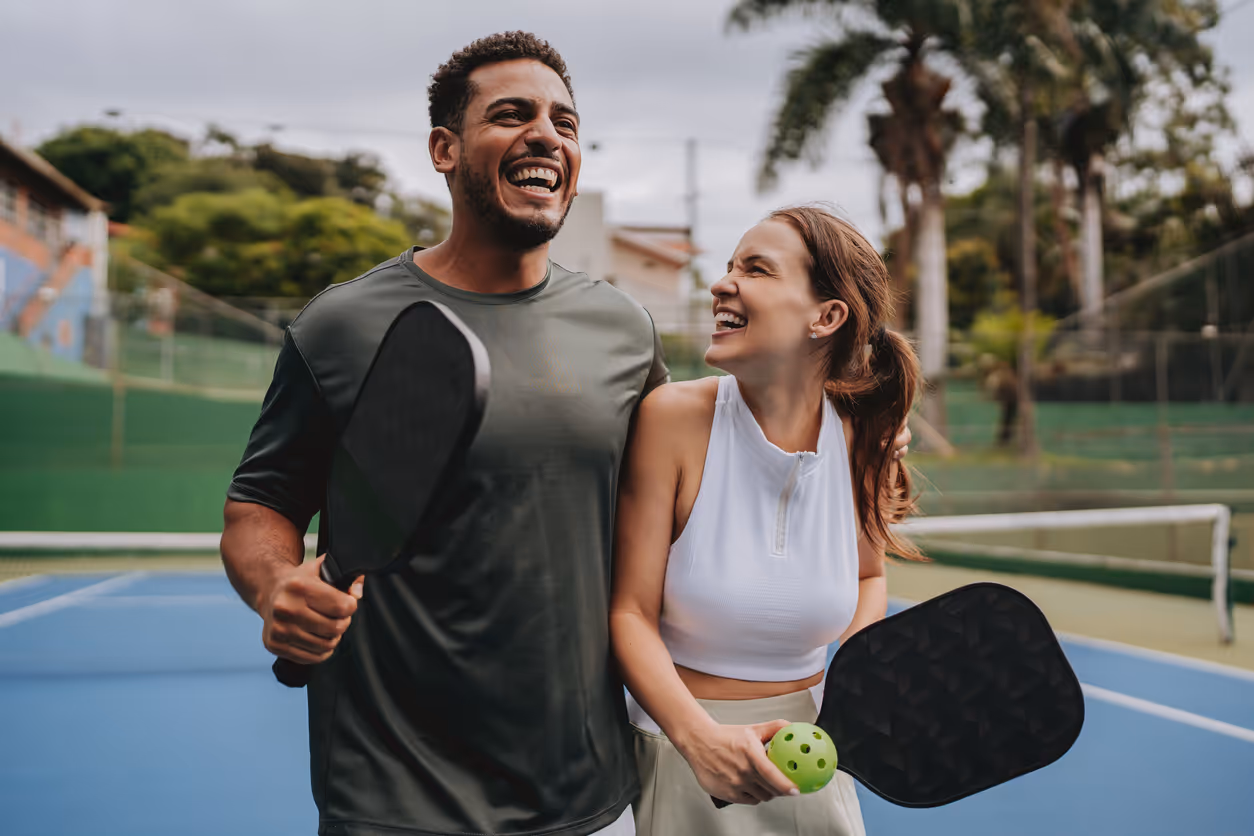 Ein Paar spielt gemeinsam Pickleball und feiert jubelnd einen gewonnenen Punkt.