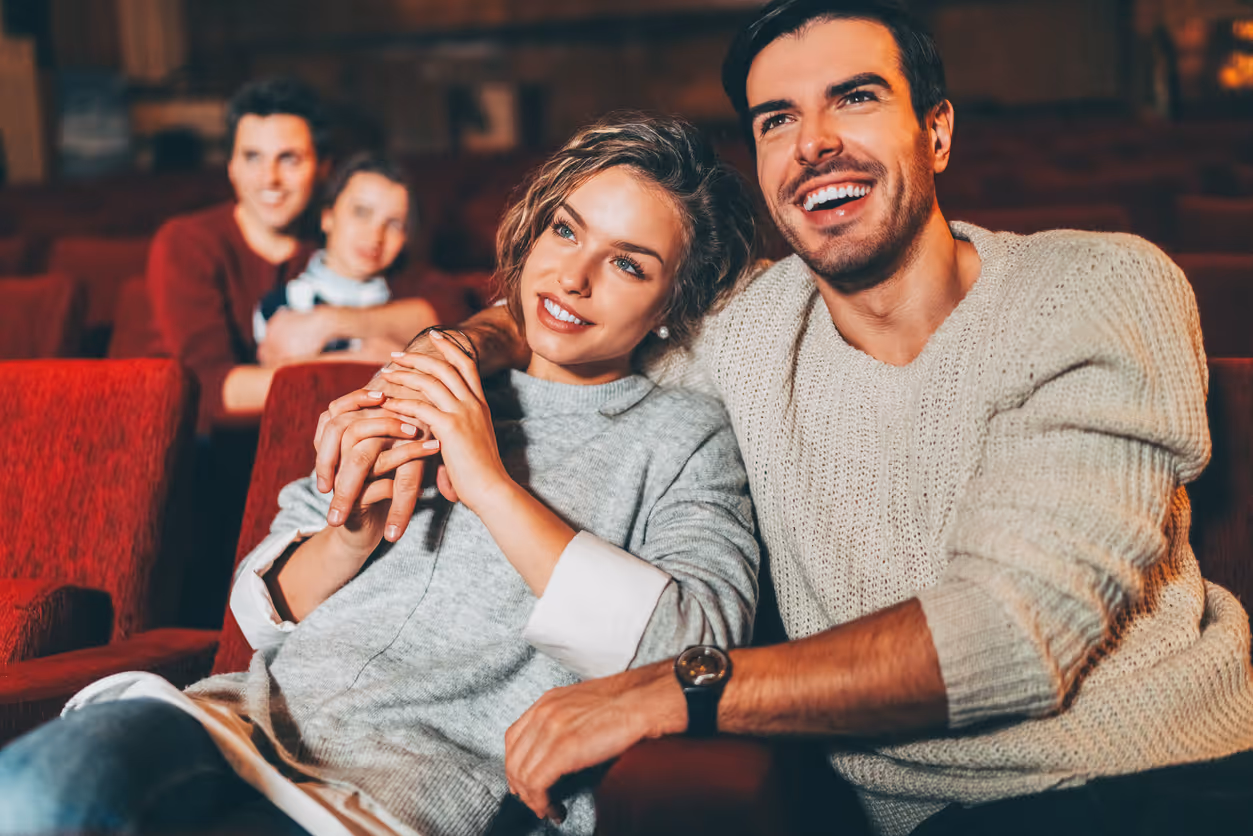 Zwei Paare sitzen gemeinsam im Kino und schauen aufmerksam einen Film.