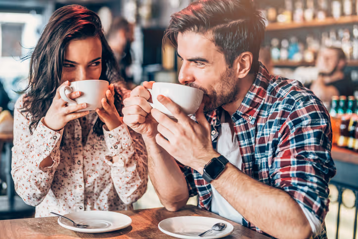 Junges Paar trinkt Kaffee und schaut sich verliebt an