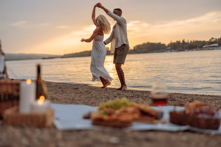 anzendes Paar an einem Strand mit einem verschwommenen Picknick im Vordergrund.