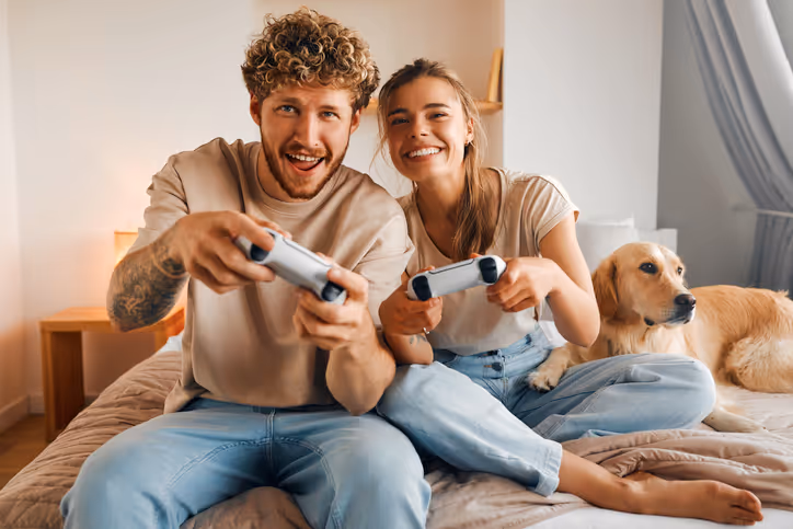 Paar mit Golden Retriever beim Gameboy spielen im Wohnzimmer
