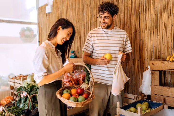 Paar kauft auf dem Markt Gemüse und Obst ein