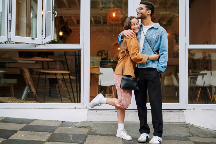 Paar umarmt sich vor einem Café mit Glasfront