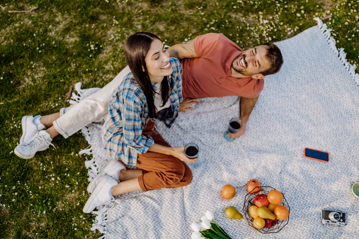 Zwei Personen genießen ein Picknick im Park mit Früchten und Wein