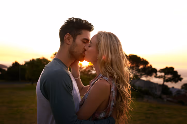 Junges Paar küsst sich bei Sonnenuntergang im Park