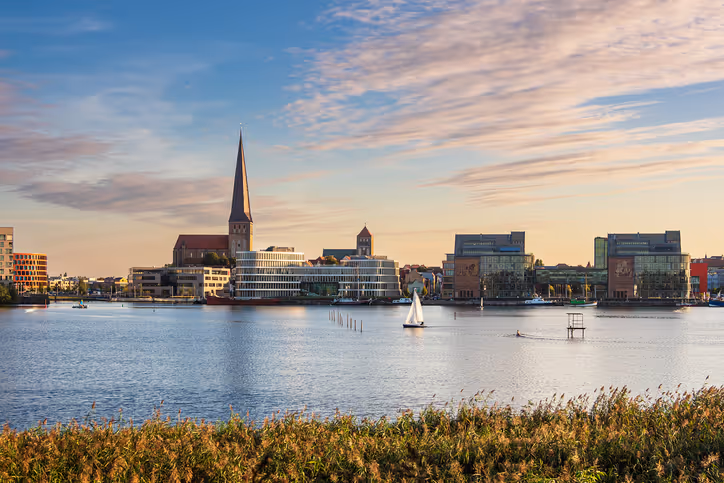 Stadtpanorama von Rostock mit Kirche und modernen Gebäuden am Ufer eines Flusses