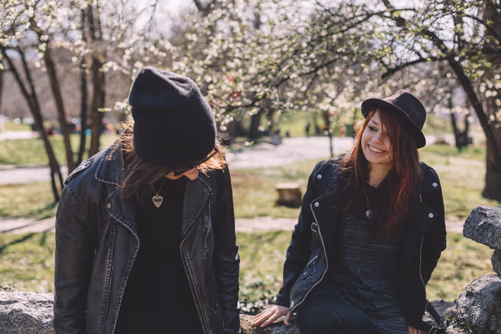  Ein junges Paar sitzt im Freien auf einer Mauer und lacht miteinander