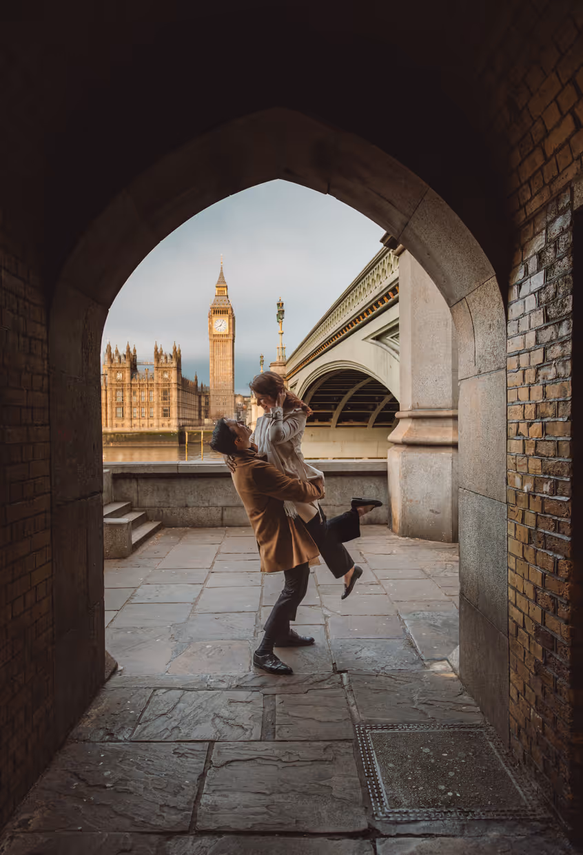 Mann hebt Frau unter einem Steinbogen hoch
