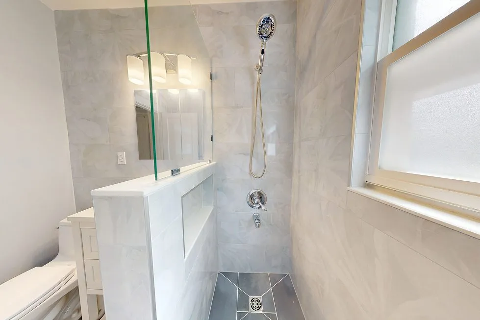 Finished walk-in shower with a tiled niche, pony wall and marble-look wall tile