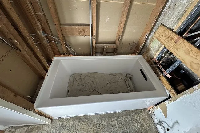 A new bathtub set into the exposed framing during the Queen Anne bathroom rebuild
