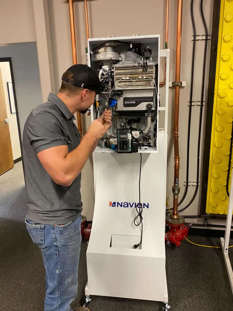 Technician repairing a Navien water heater in a mechanical room