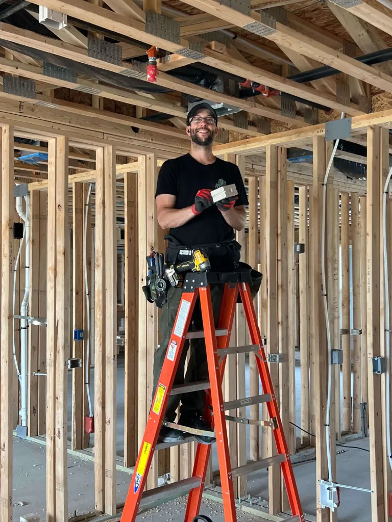 Smiling construction worker on orange ladder inside wooden framed building