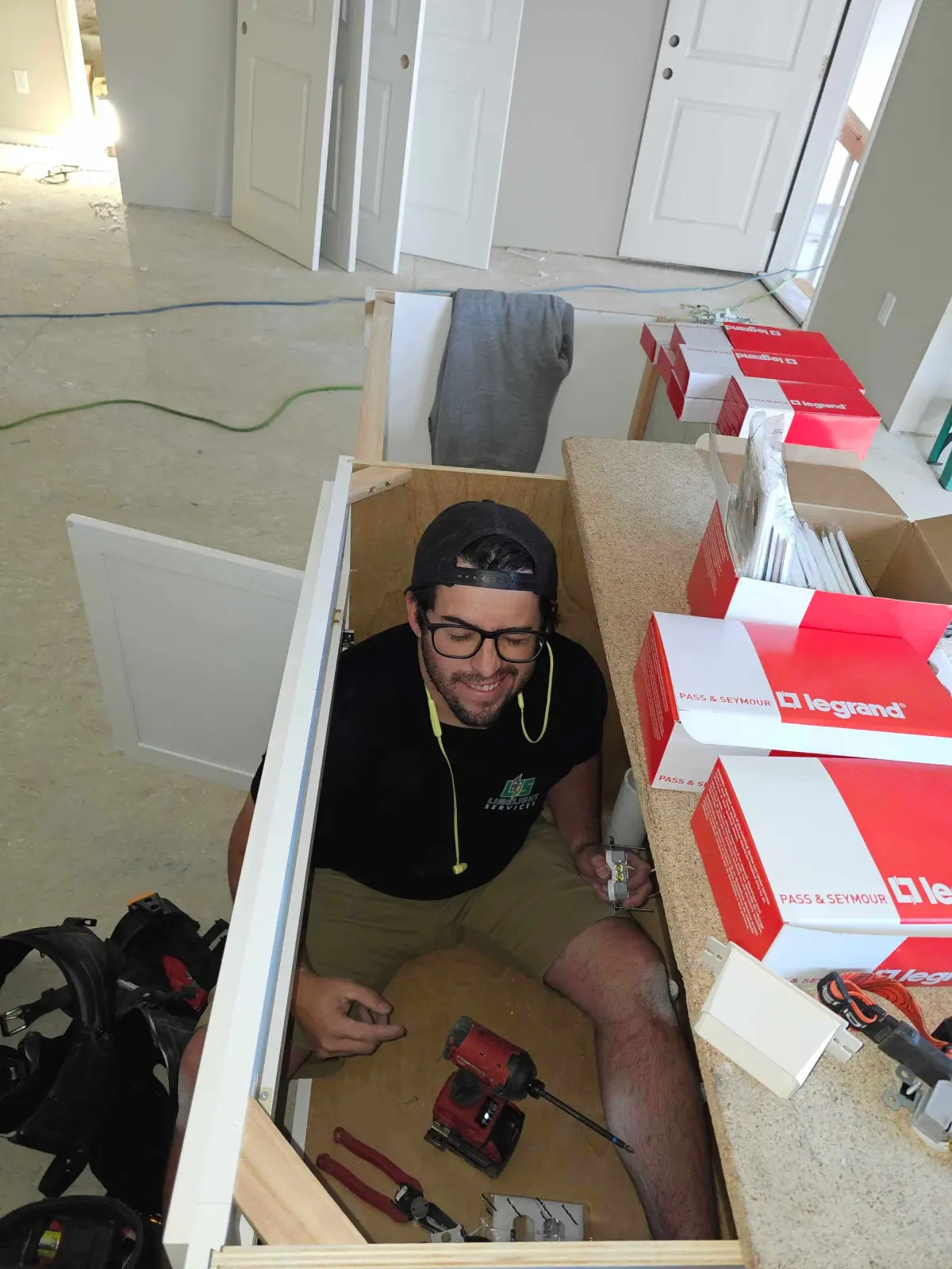 Smiling technician working inside a narrow electrical installation compartment
