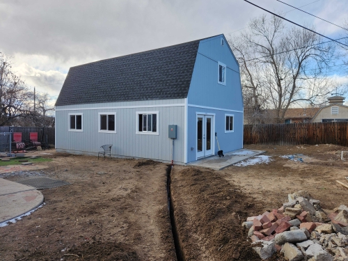 Blue and white house under construction with trench and landscaping rocks