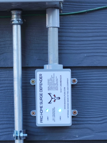 White surge protector mounted on blue wooden wall with metal pipes