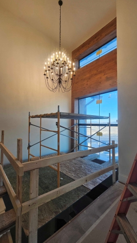 Elegant chandelier above wooden scaffolding in bright, high-ceilinged interior