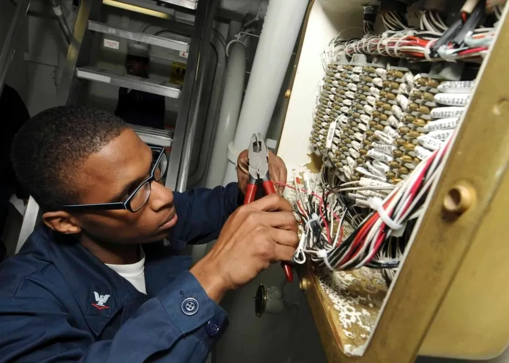 Technician cutting wires on circuit board.
