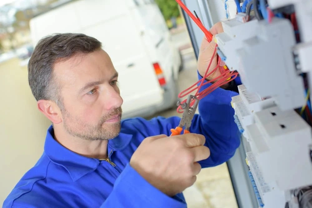 Electrician repairing a residential fuse box.