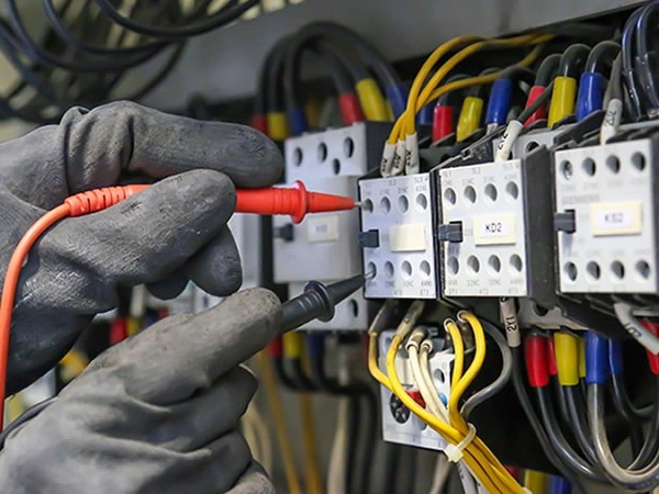 Electrician testing commercial contactors with multimeter.