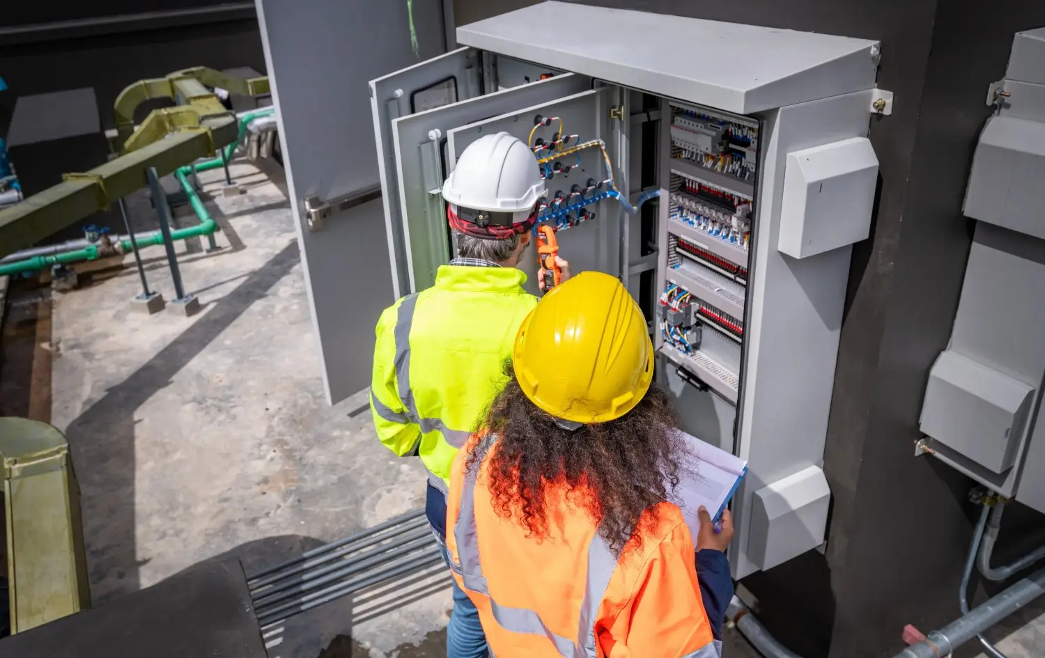 Electrical engineers inspecting control panel.