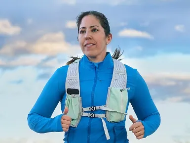 Shannon running outside in a blue jacket wearing a running vest.