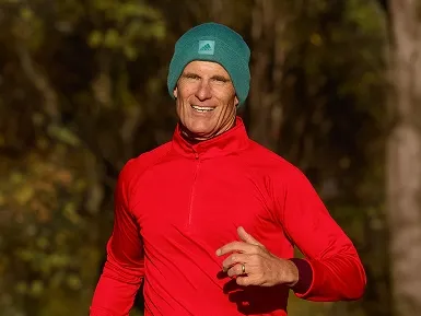 Hale running outside in a green beanie and a red long sleeved top.