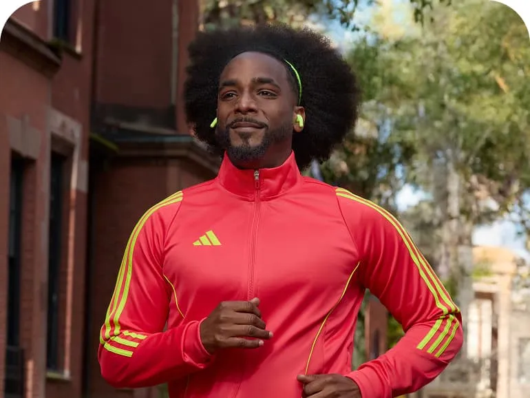 Chazz running outside with a red and yellow Adidas track top.