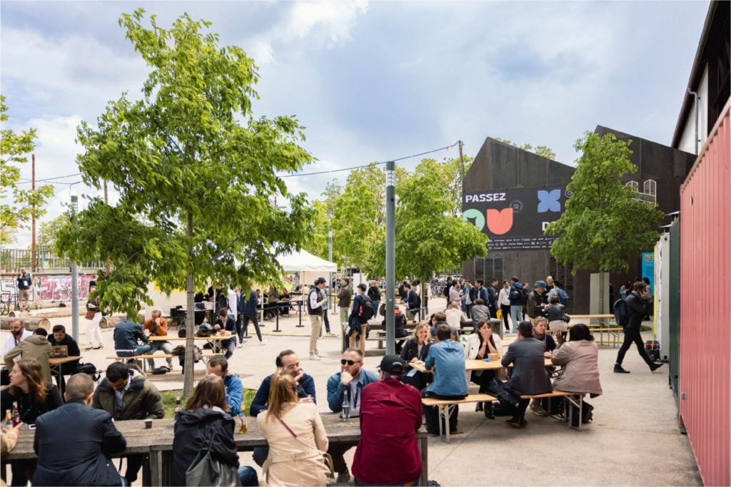 Photo des tables en extérieur avec des gens qui discutent