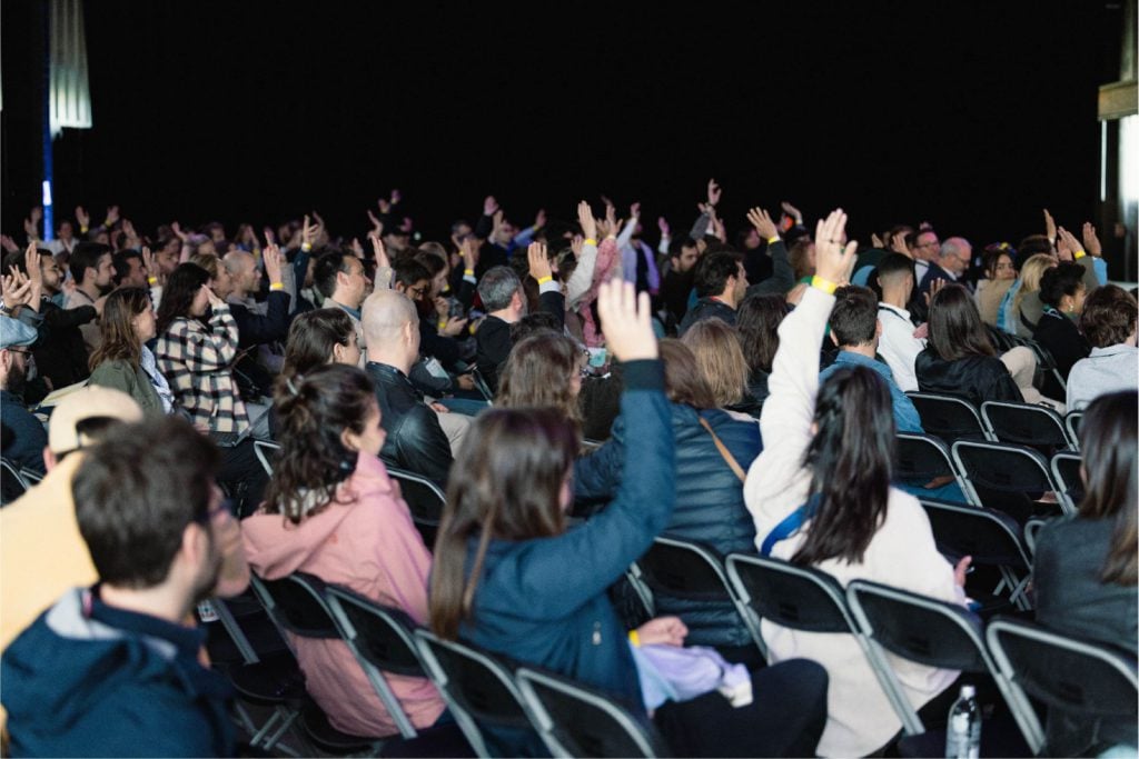 Photos de participants le bras levés pendant une conférence
