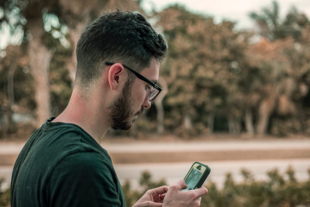 Jeune home réservant un billet sur son téléphone
