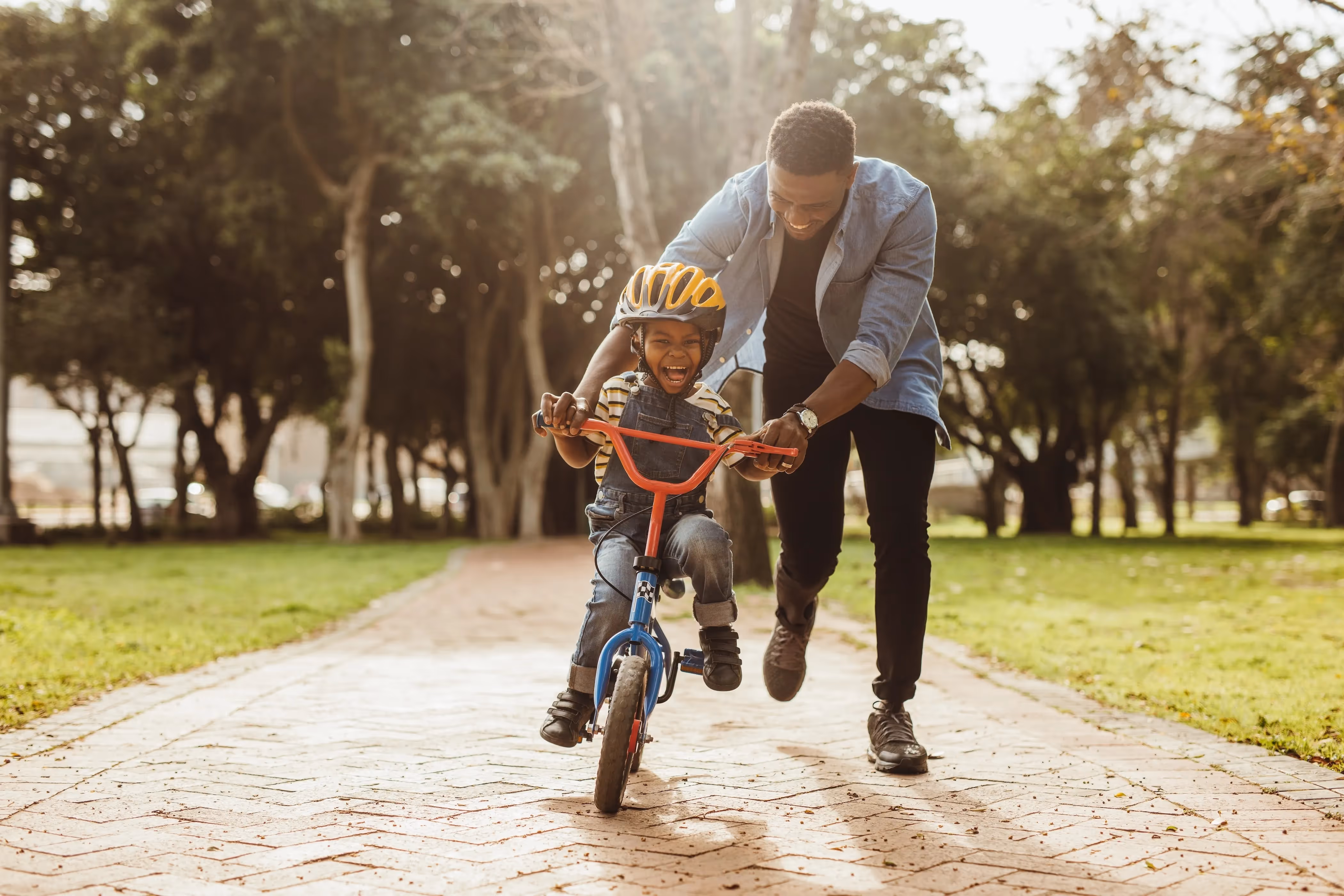 father pushing son on bike stock image
