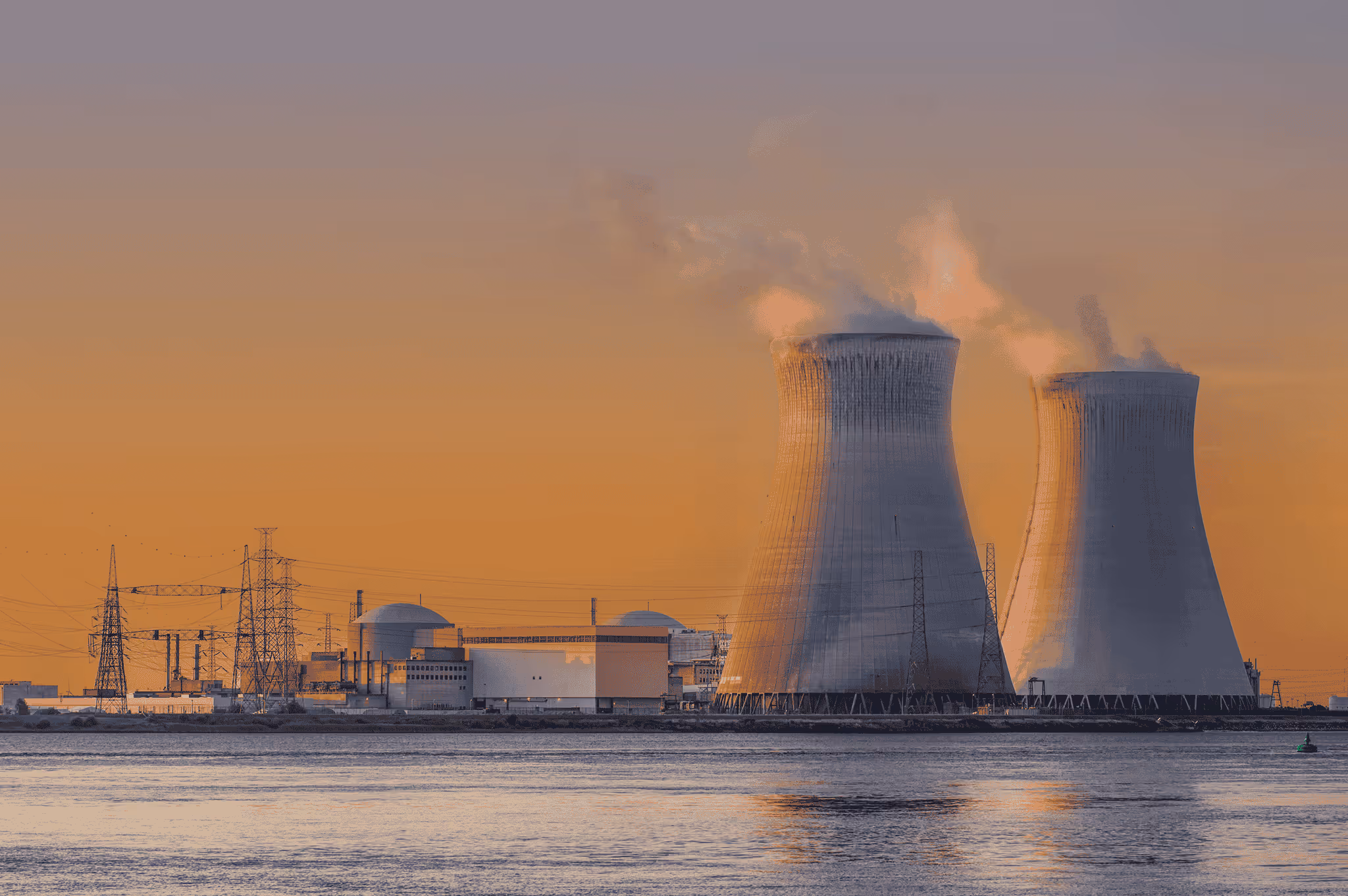 A power plant with an orange sunset in the background.