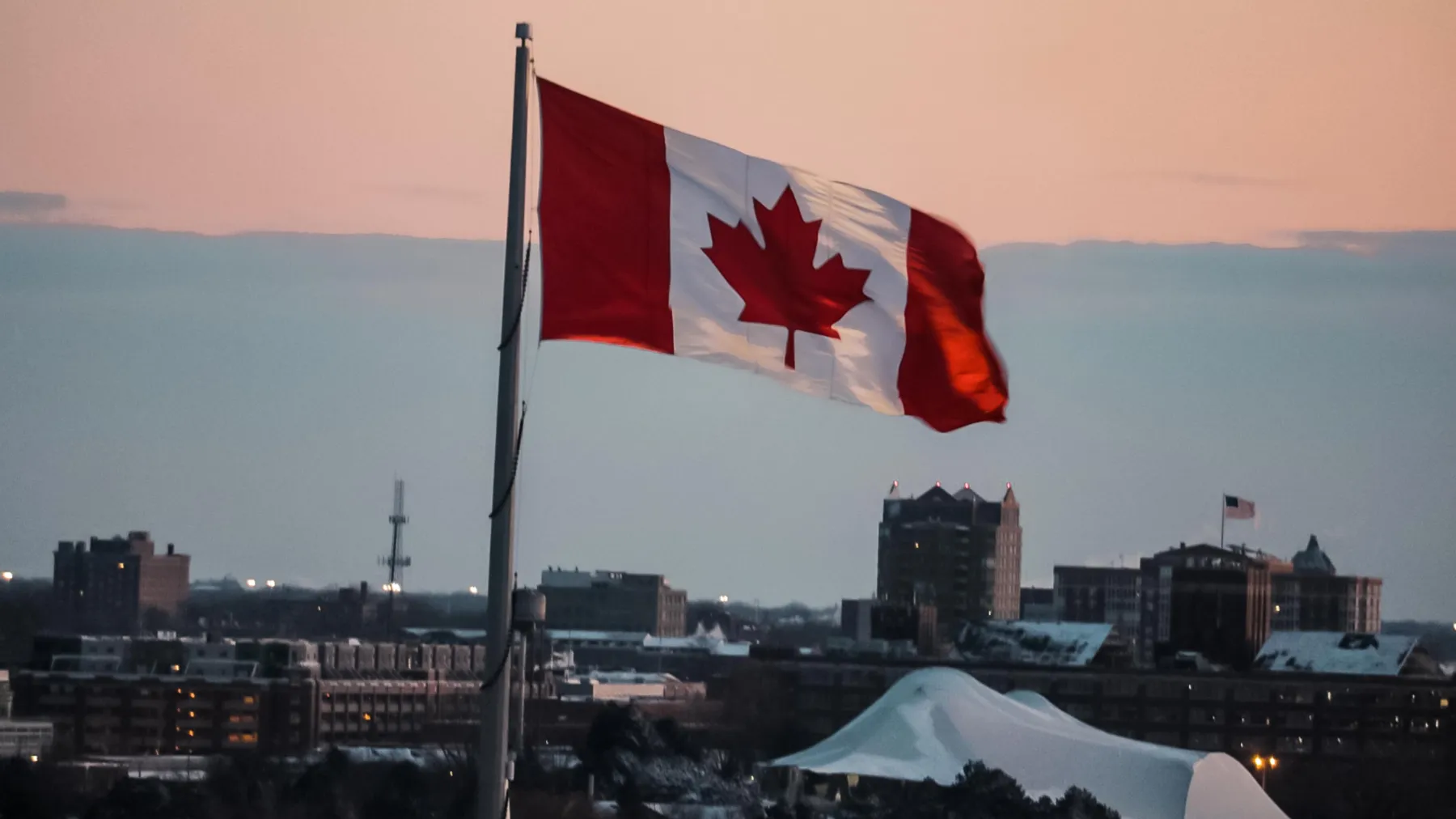 Canadian flag in front of cityscape.