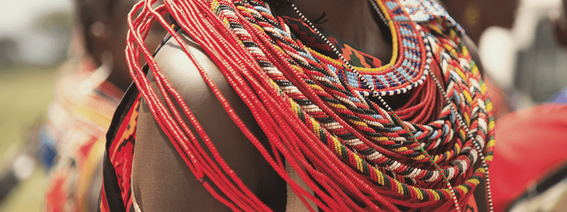 Close-up of person wearing layered, colorful beaded necklaces and traditional attire.