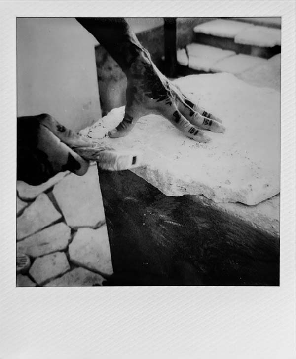 Two hands hammering at stone to make a table top.