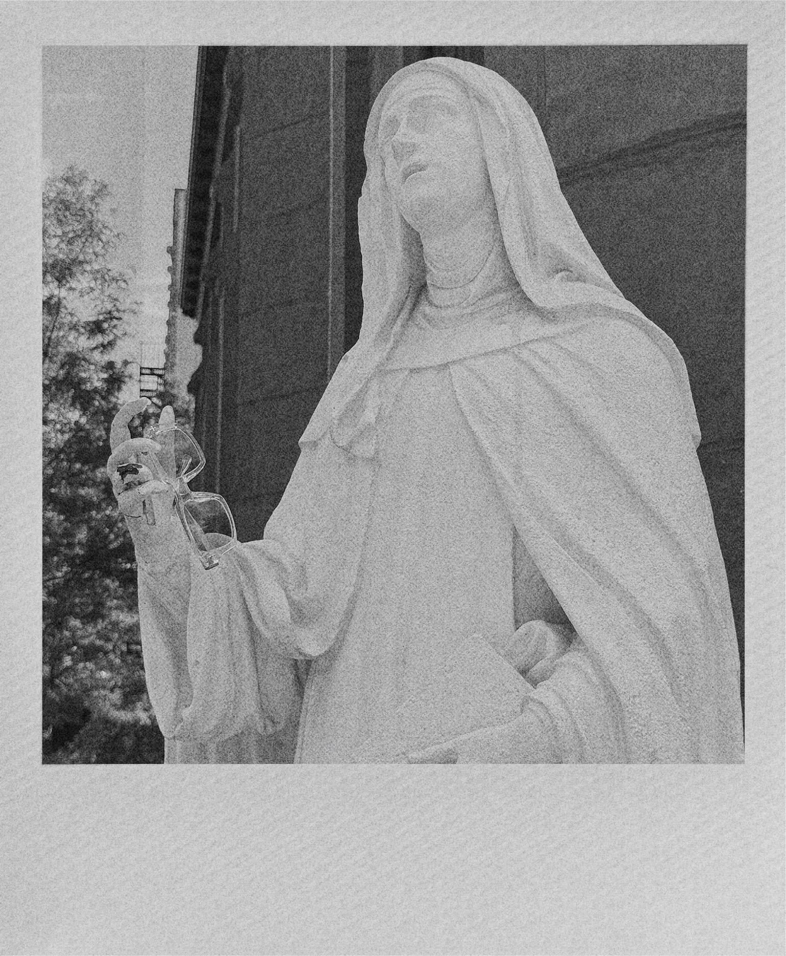 A white marble statue of Mary Magdeline holding a pair of Sloen sunglasses.