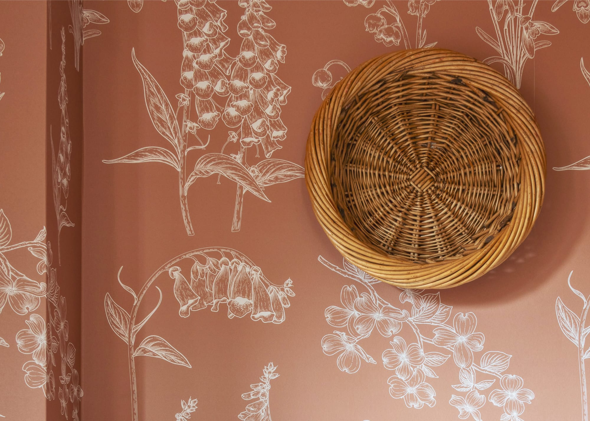 A custom designed wallpaper with a decorative circular weaved basket attached to the wall.