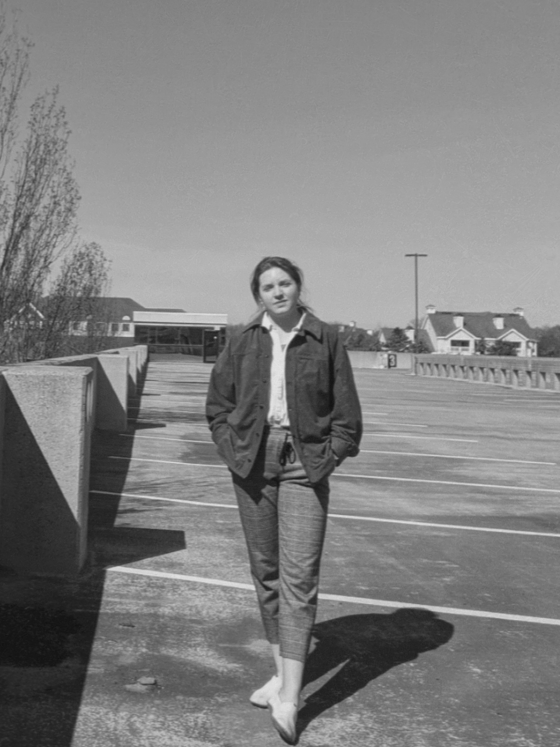 Susannah posing in a garage wearing a jacket they sewed