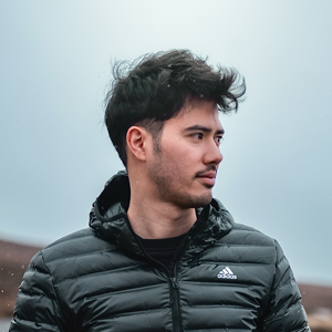 profile picture, looking to the side in a mountain area with blue sky behind